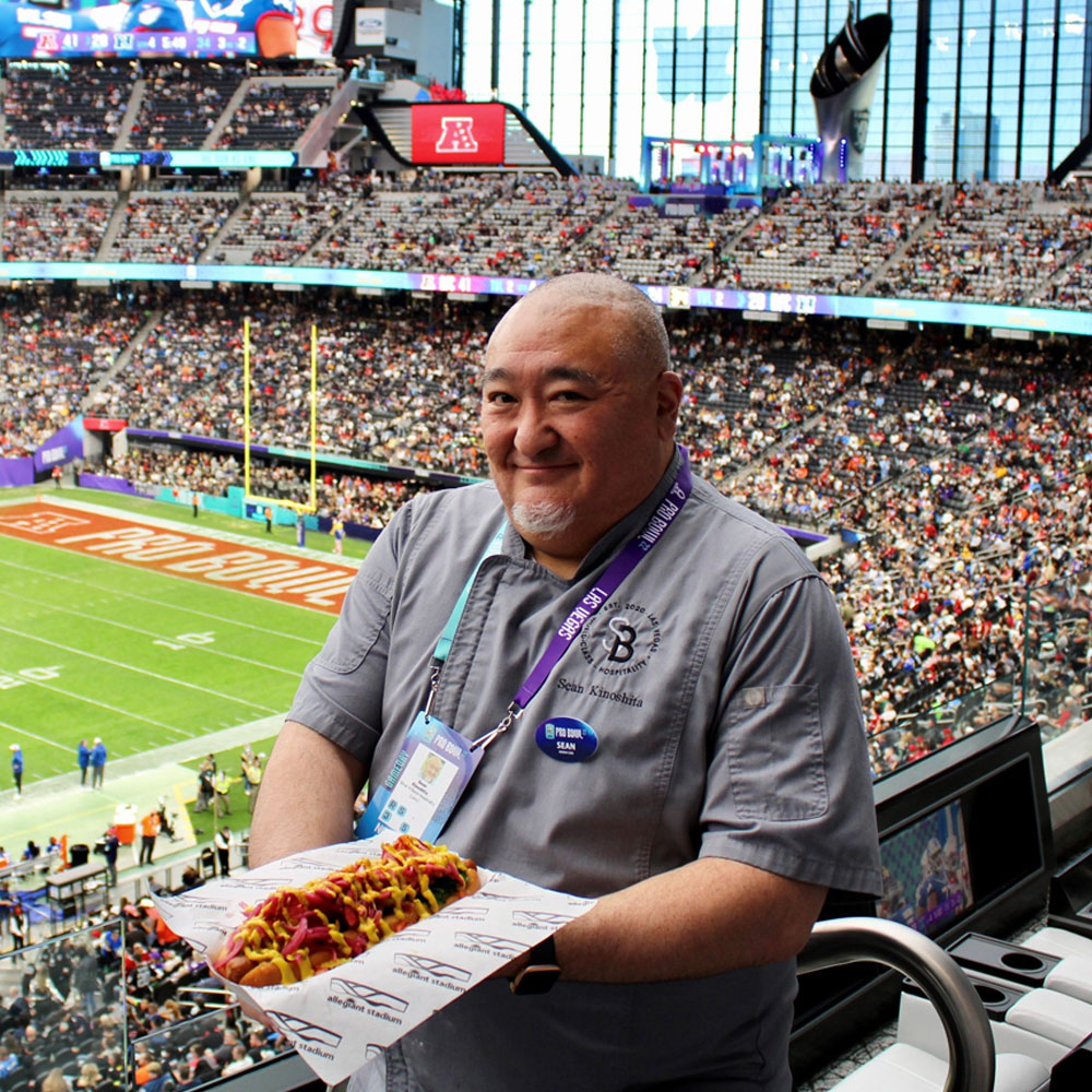 man showing off food in front of a stadium