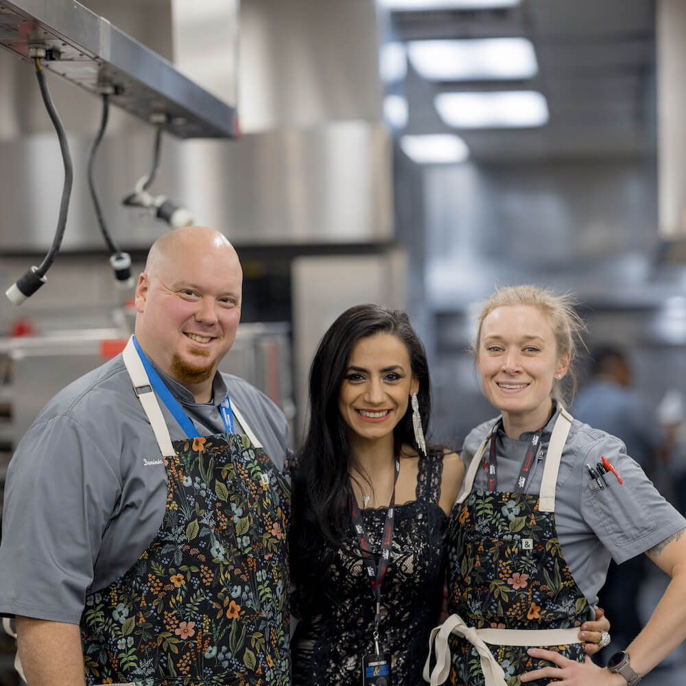 three team members posing in a kitchen