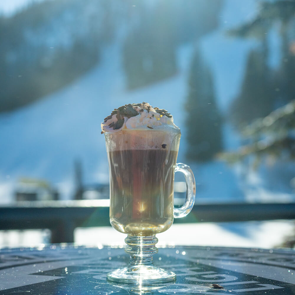 fancy hot chocolate in a mug in front of a snowy scene