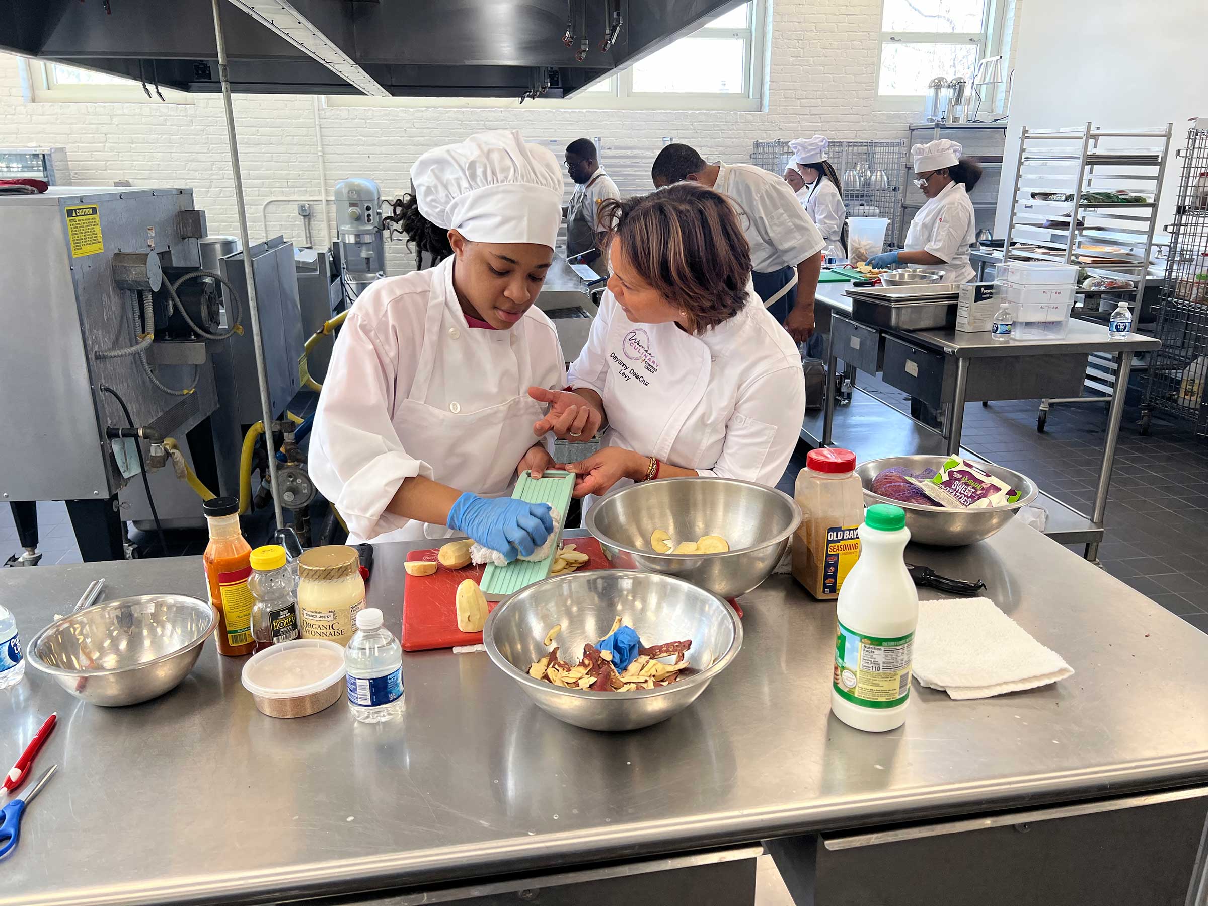 Chef Dayanny Delacruz showing a student how to properly use a mandoline