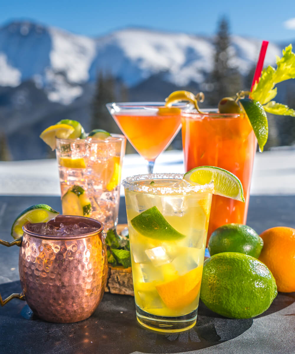 collection of colorful drinks with a ski mountain in the background