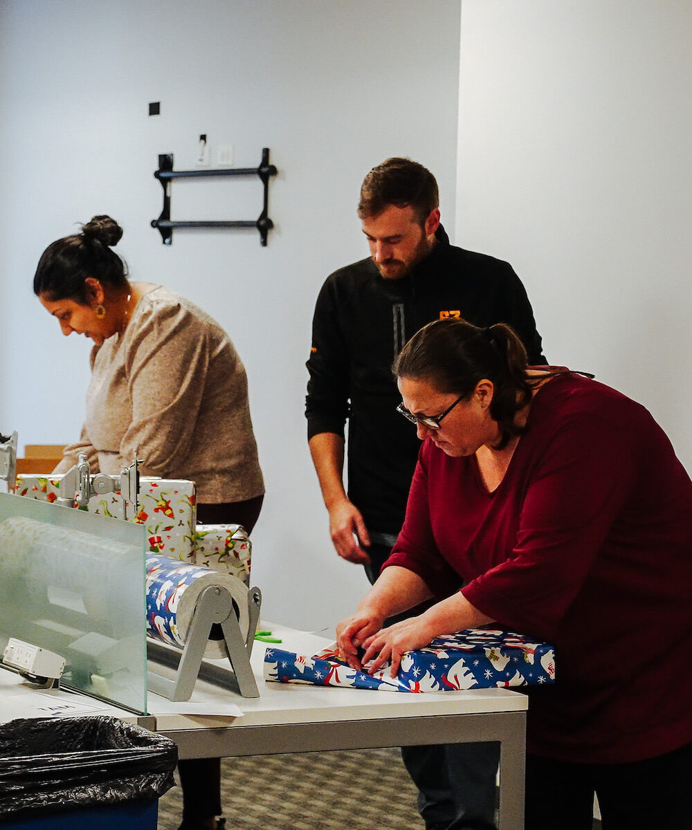 team members wrapping gifts - mobile version