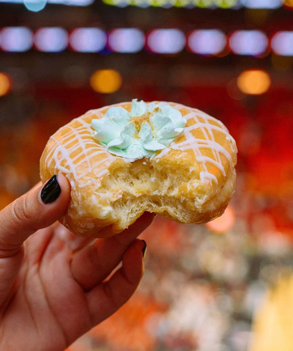 a hand holding a donut in front of a stadium crowd - mobile version