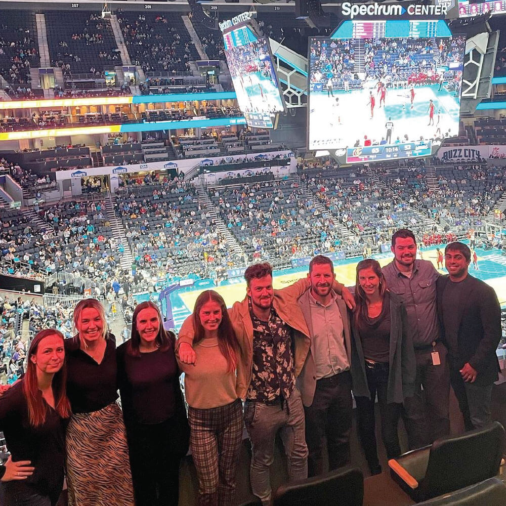 A team of employees in front of a large, packed stadium