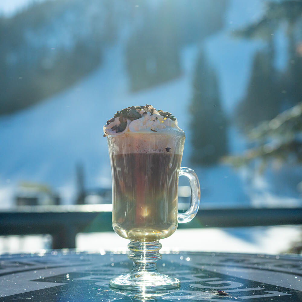 fancy hot chocolate in a mug in front of a snowy scene