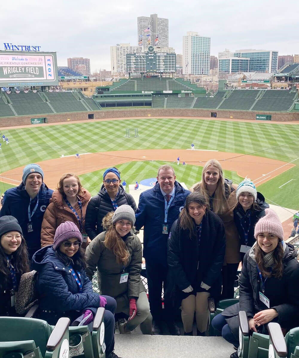 A group of employees posing in front of a large baseball stadium - Mobile Version