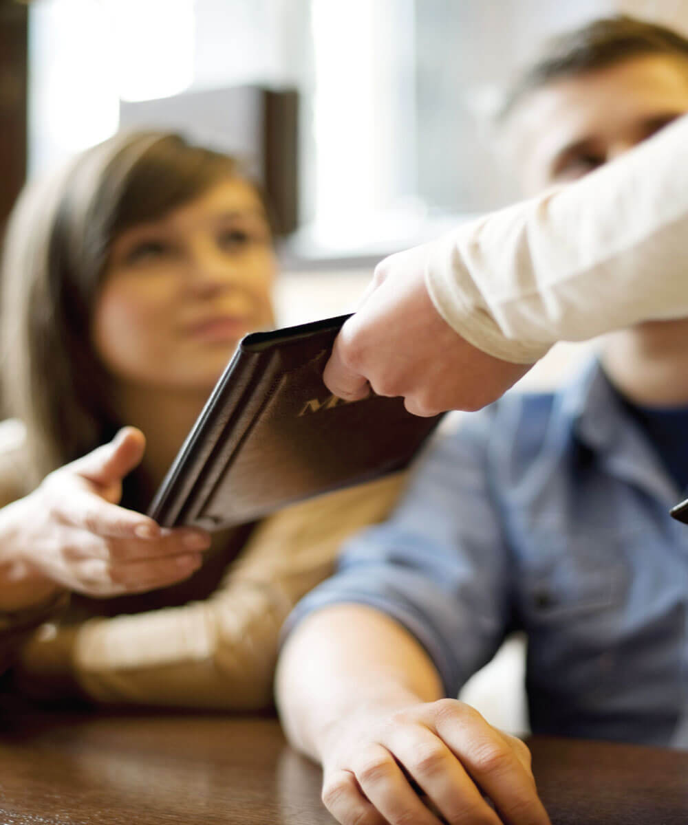 waitress handing menus to patrons - Mobile