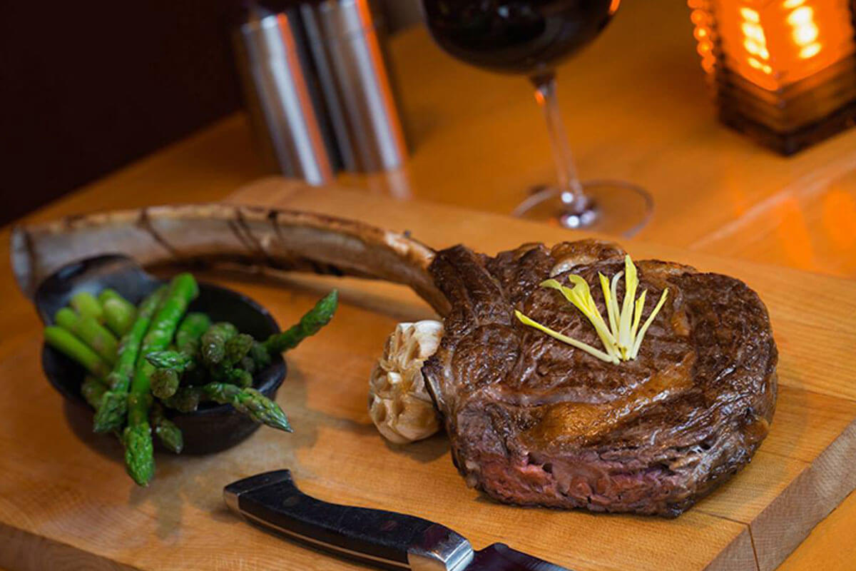 A thick tomahawk steak with green beans