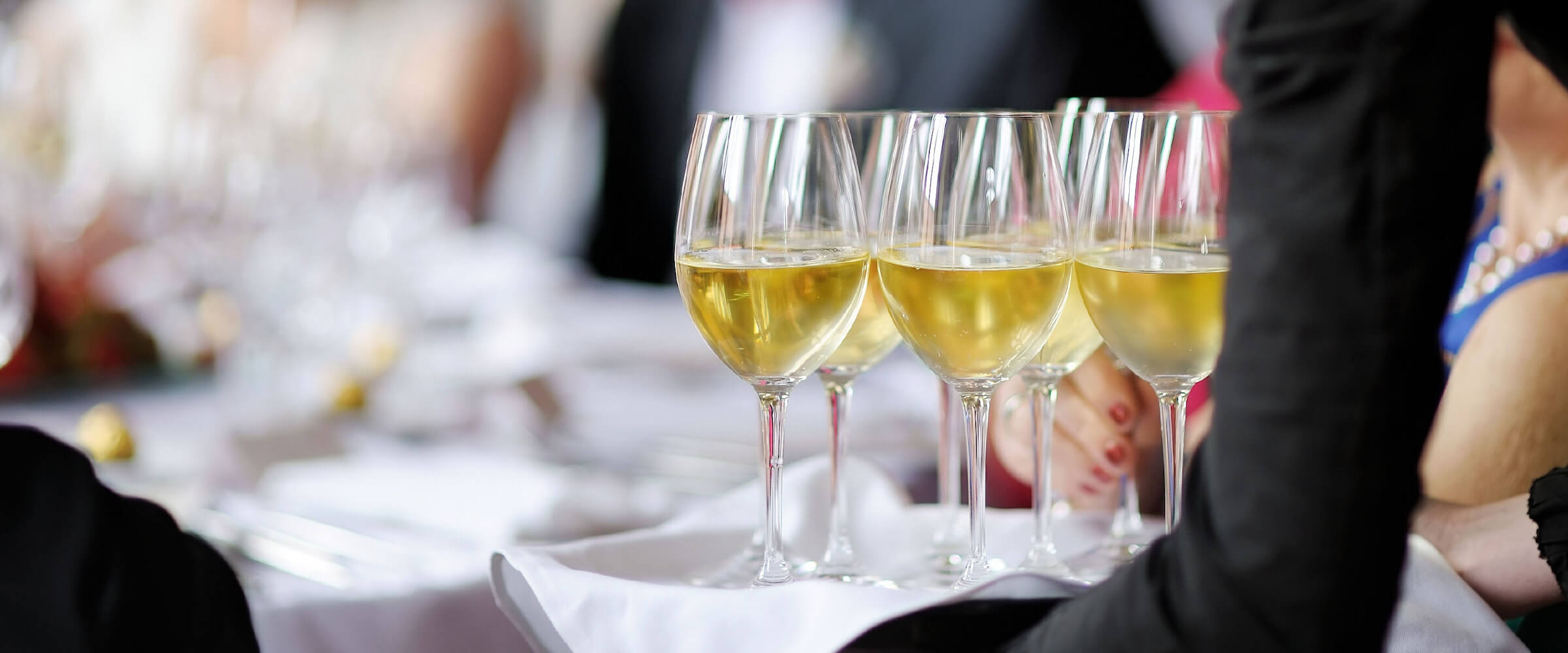 wine glasses being served to a table of guests - desktop version